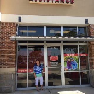 A person standing in front of a storefront entrance on a sunny day.