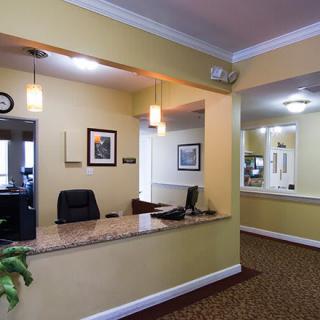 A well-lit office reception area with a desk and hallway in view.