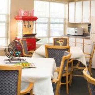 A cozy room with tables and chairs, featuring a popcorn machine and bingo setup.