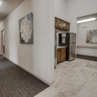 A modern hallway with a kitchenette and artwork on the walls.