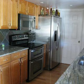 A modern kitchen with stainless steel appliances, wood cabinets, and a granite countertop.