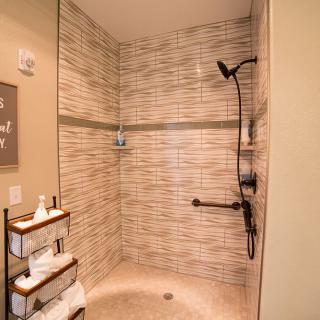 A modern walk-in shower with beige tiles and a wall-mounted showerhead.