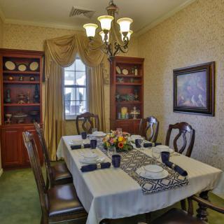 A traditional dining room with an elegantly set table and a chandelier.