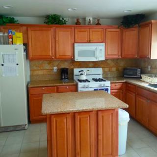 A modern kitchen with wooden cabinets, a central island, and various appliances.