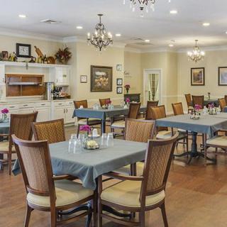 A cozy dining area with neatly arranged tables and chairs, adorned with chandeliers and elegant decor.