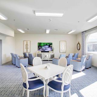 A bright living room with a seating area, television, and dining table.
