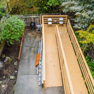 An outdoor bocce court surrounded by lush greenery and a wooden fence.