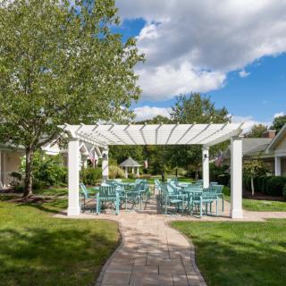 Outdoor pergola with turquoise chairs on a sunny day.