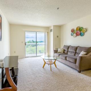 A bright and cozy living room with a comfortable sofa, a stylish coffee table, and decorative wall art, illuminated by natural light from the sliding glass door.
