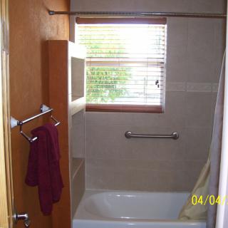 A bathroom with a bathtub, window, and towel hanging on the rack.