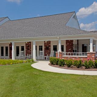 A beautiful residential building featuring a spacious porch and well-maintained lawn.