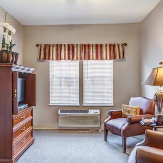 A cozy living room with a TV, sofa, and a window letting in natural light.