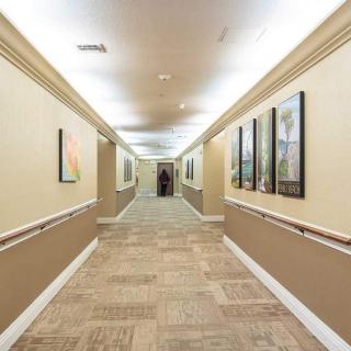 A well-lit hallway with artwork on the walls and tiled flooring.