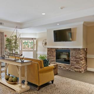 A modern living room with a stone fireplace, wall-mounted TV, and comfortable seating.