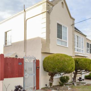 A suburban residential house with manicured trees and a red fence.