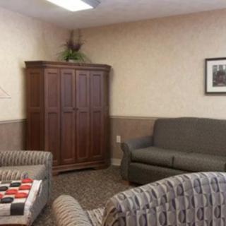 A cozy living room with a sofa, armchairs, and a large cabinet.
