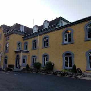 A charming two-story building with a yellow exterior and multiple windows, surrounded by well-maintained landscaping.