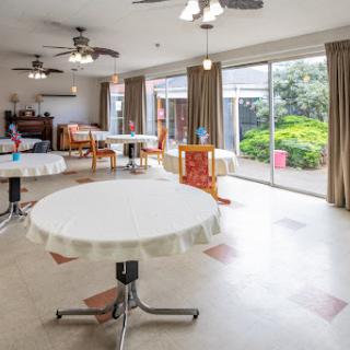 A bright and spacious dining area with tables set up for meals, featuring large windows that allow natural light to fill the space.