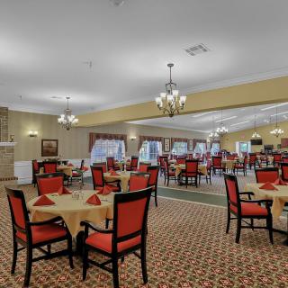 A spacious dining area with red-accented chairs and elegant chandeliers.