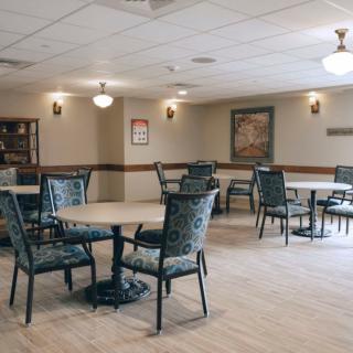 An empty dining area with tables and chairs arranged neatly under ceiling lights.