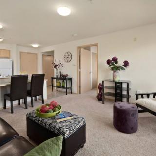 A modern living room with an open floor plan, featuring a cozy seating area and adjacent dining space.