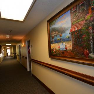 A well-lit hallway with a colorful painting on the wall.