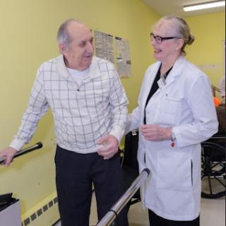 A healthcare professional assisting an elderly patient during a rehabilitation session.