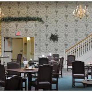 An elegant dining area with chandeliers, neatly arranged tables and chairs, and a decorative wallpaper design.