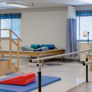 A well-equipped physical therapy room featuring exercise mats and parallel bars for rehabilitation.
