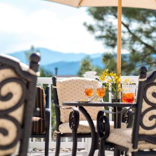 A scenic outdoor patio with drinks on the table, offering a view of the mountains.