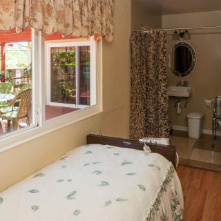 A cozy bedroom with an adjacent bathroom, featuring floral decor and a large window.