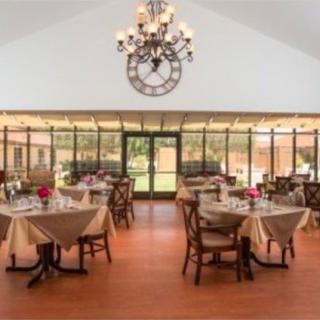 An elegant dining area with neatly arranged tables, chairs, and a large chandelier overhead.