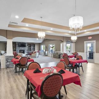 This image shows a well-lit dining room with red tablecloth-covered tables and elegant chandeliers.