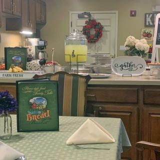 A cozy kitchen and dining area with a table set for dining, featuring a lemonade dispenser and decorative elements.