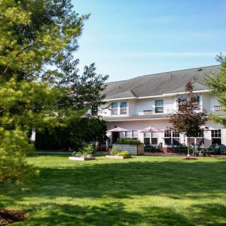 A two-story house with a large lawn and trees in the background.