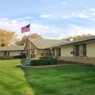 A residential building with a well-maintained lawn and an American flag flying in the foreground.
