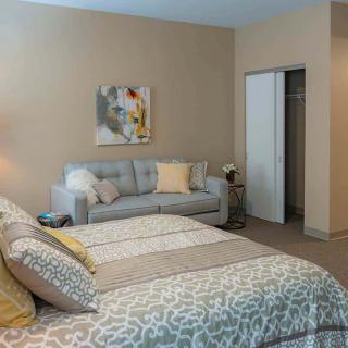 A cozy bedroom with a bed, sofa, and artwork on the wall.