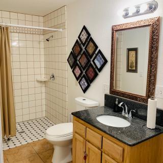 A neatly designed bathroom with a mirror, sink, toilet, and tiled shower area.
