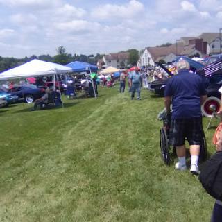 A bustling car show with various vehicles on display under clear skies.