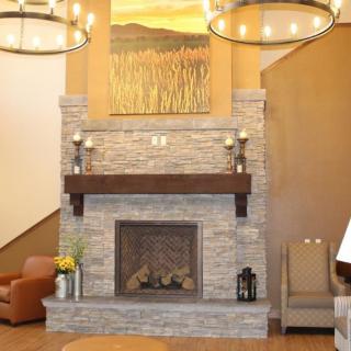 A cozy living room with a stone fireplace, decorated mantel, and elegant chandeliers.