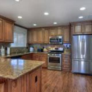 A modern kitchen with wooden cabinets, granite countertops, and stainless steel appliances.