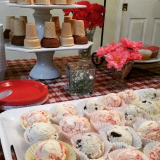 A festive dessert table featuring assorted ice creams and cone treats.