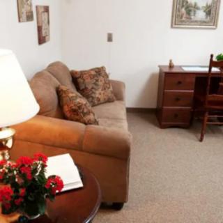 A cozy living room with a sofa, desk, and lamp.