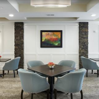 A modern dining area with tables, comfortable chairs, and colorful artwork on the wall.