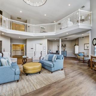 A spacious and modern living room with blue sofas, an open floor plan, and a mezzanine balcony.