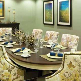 A beautifully arranged dining room featuring an elegant table setting with floral chairs and framed artwork on the walls.