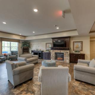A modern and comfortable living room with ample seating, featuring a fireplace and television.