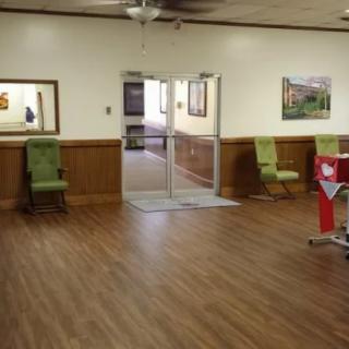 A cozy lobby area with wooden flooring and green chairs near the entrance.