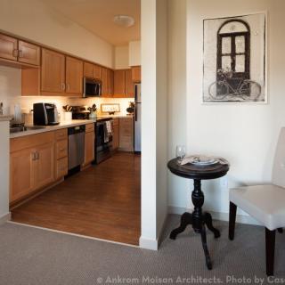 A modern apartment interior featuring a compact kitchen and cozy living area with artwork on the wall.