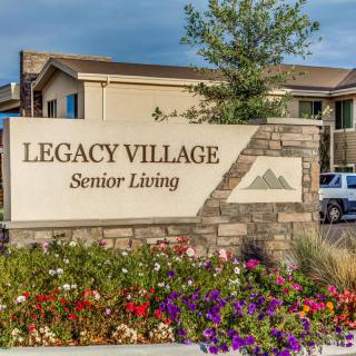 Entrance sign for Legacy Village Senior Living, surrounded by landscaped flowers.